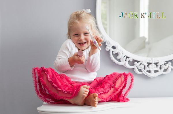 Niña sentada sobre una mesa sosteniendo un cepillo de dientes