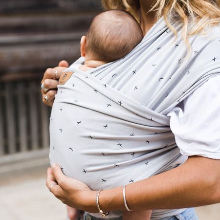 mujer porteando a bebe con fular blanco roto con cruces blancas pequeñas