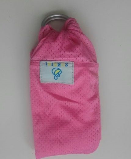 Bandolera portabebé doblada color rosa.