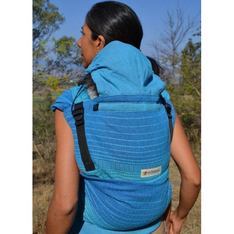 Mujer de espaldas porteando a bebé en la espalda con wrap tai color azul