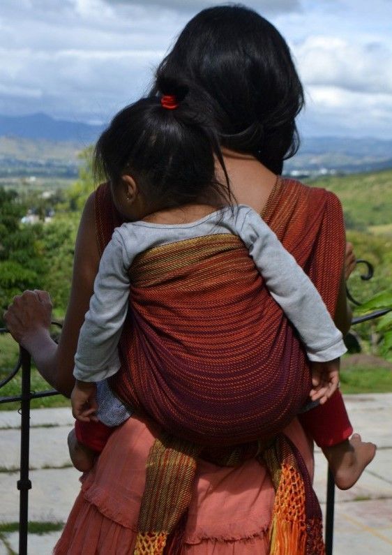 Mujer con niña porteando con rebozo tradicional mexicano color naranja
